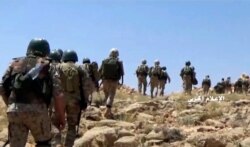 FILE - This frame grab from video released July 22, 2017, and provided by the government-controlled Syrian Central Military Media, shows Hezbollah fighters advancing up a hill in an area on the Lebanon-Syria border.