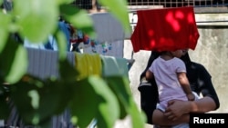 A Rohingya child bride who ran away from her husband carries her sister outside a shack she shares with her mother and siblings, on the outskirts of Kuala Lumpur, Malaysia, Feb. 9, 2017.