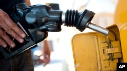 FILE - A customer pumps gas into his dual-tank pickup truck at a 76 gas station in Los Angeles, Aug. 10, 2012. 