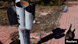 A stray cat named "Whiskas" by the battalion stationed in this undisclosed location near the frontline town of Kreminna walks past a a tail section of a rocket, in Ukraine March 14, 2023. 