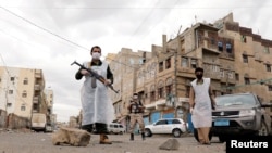 FILE - Security officers wearing protective masks stand on a street during a 24-hour curfew amid concerns about the spread of the coronavirus, in Sanaa, Yemen, May 6, 2020.