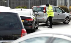 FILE - People queue in their cars at a drive-through coronavirus testing site in an IKEA parking lot in the Wembley area of London, Britain, April 1, 2020.