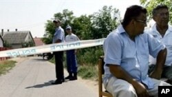 Local citizens sit on their chairs as Hungarian policemen secure the area after gunmen shot dead a Roma in Kisleta village, about 260 kms east from Budapest (File Photo)