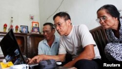 FILE - Veteran Le Dung (C) reads articles on the Internet with Dang Van Dat (L) and Tran Thi Thanh Kiem (R) at his house in Van Giang district, outside Hanoi, Vietnam.