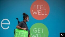 A woman walks past a logo outside a pharmacy in Alberton, near Johannesburg, South Africa, Jan. 7, 2021. 