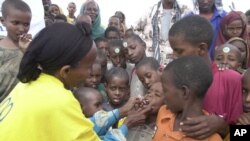 FILE - A World Health Organization official dispenses polio vaccine in Tosweyn village, Somalia. Investing in children's health and education spurs countries' economic development, a new U.N. report says. 