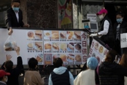A worker hands down a bag of bread outside a bakery in Beijing, March 23, 2020. While social distancing remains the norm, China is striving to restore activity in the world's second-largest economy after the shutdown over the coronavirus outbreak.