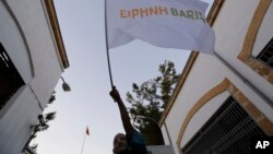 A supporter for peace waves a flag reading "Peace" in Greek and Turkish, as in the background a Turkish flag flies, at Ledras main crossing point inside the U.N buffer zone that divided the Greek and Turkish Cypriots controlled areas, Nicosia, Cyprus, Jun