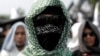 An Islamic group member covers his face with Hizbut Tahrir flag during a protest against the decree allowing the government to disband organizations deemed to run counter to the secular state, in Jakarta, Indonesia, July 28, 2017. 