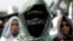 An Islamic group member covers his face with Hizbut Tahrir flag during a protest against the decree allowing the government to disband organizations deemed to run counter to the secular state, in Jakarta, Indonesia, July 28, 2017. 