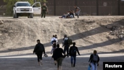 Se ve a los migrantes después de cruzar ilegalmente a Estados Unidos para entregarse y solicitar asilo en El Paso, Texas.