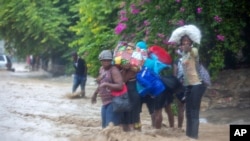 People cross a flooded street during the passing of Tropical Storm Laura in Port-au-Prince, Haiti, Aug. 23, 2020.