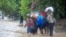 People cross a flooded street during the passing of Tropical Storm Laura in Port-au-Prince, Haiti, Aug. 23, 2020.