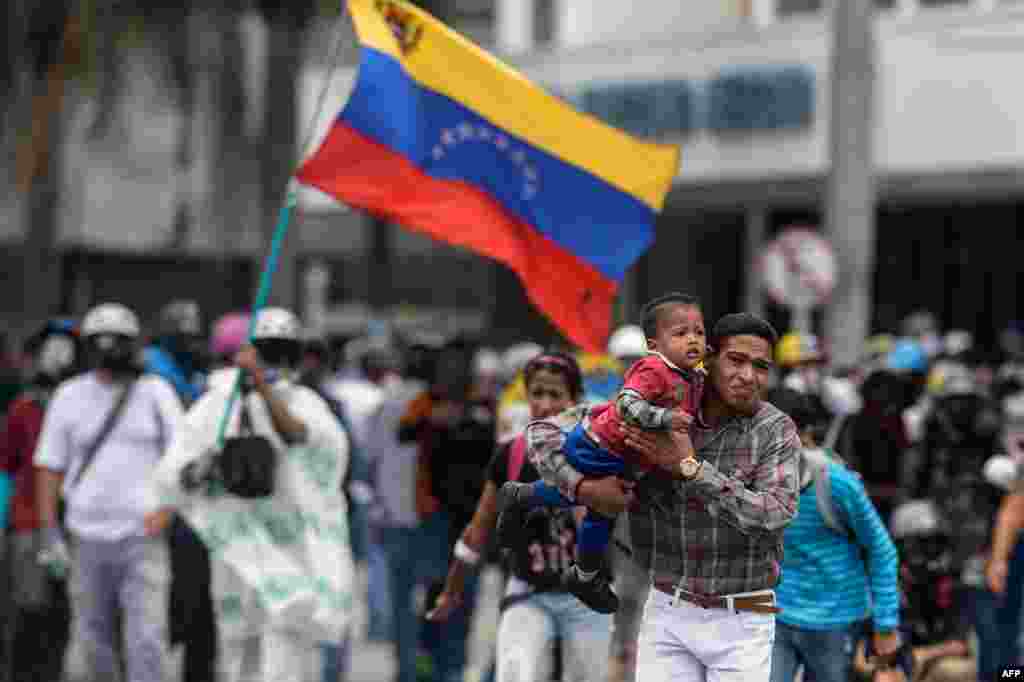 Orang-orang menyingkir saat terjadi bentrokan antara pengunjuk rasa kaum oposisi dan polisi anti huru-hara dalam unjuk rasa menentang pemerintahan Presiden Nicolas Maduro di Caracas, Venezuela.