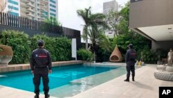In this photo distributed by Colombia's Attorney Generals Office, officials pose with their backs to the camera by a pool on a property allegedly belonging to Alex Saab in Barranquilla, Colombia, July 22, 2020.