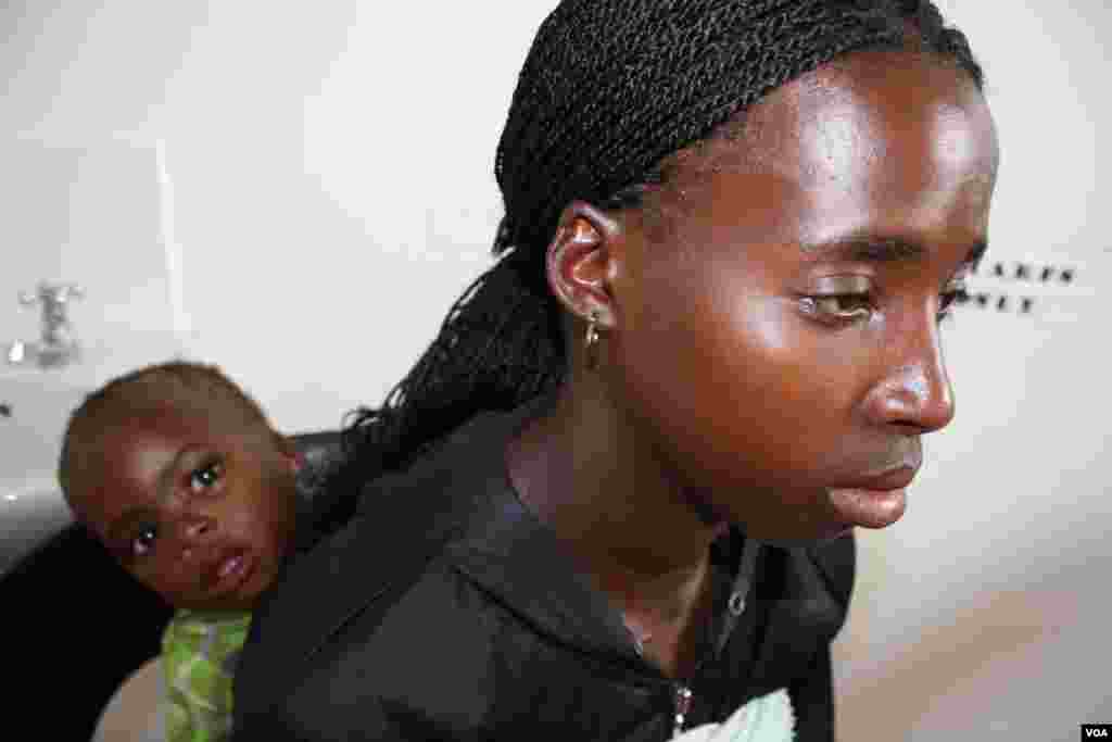 Sixteen year old Thembakazi Mdluli waits for a nurse to see her sick infant son.(VOA/D. Taylor)
