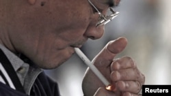 FILE - A man lights a cigarette in Los Angeles, California.