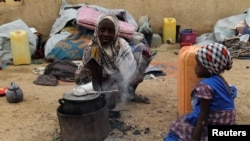 A displaced girl cooks at an arena for traditional wrestling in the town of Diffa in southeastern Niger June 20, 2016. 