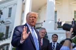 FILE - President Donald Trump, accompanied by White House Chief of Staff Mark Meadows, second from left, speaks with reporters on the South Lawn of the White House, in Washington, July 29, 2020.