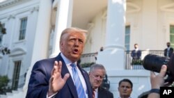 President Donald Trump, accompanied by White House Chief of Staff Mark Meadows, second from left, speaks with reporters on the South Lawn of the White House, in Washington, July 29, 2020.
