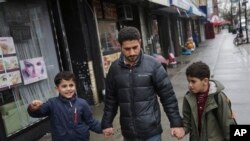 FILE - Sadek Ahmed walks with his sons Adel, 9, right, and Mutaz, 7, in New York, March 21, 2019. Their mother is stuck in Yemen with her two younger sons, the boys’ brothers. Their situation is representative of the toll the travel ban has on families.
