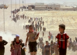 FILE - Displaced people from the minority Yazidi sect, fleeing violence from forces loyal to Islamic State militants in Sinjar, walk toward the Syrian border.