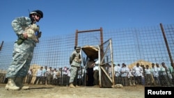 FILE - U.S soldiers stand guard as Iraqi prisoners wait to be released at Abu Ghraib prison, west of Baghdad, June 23, 2006. 