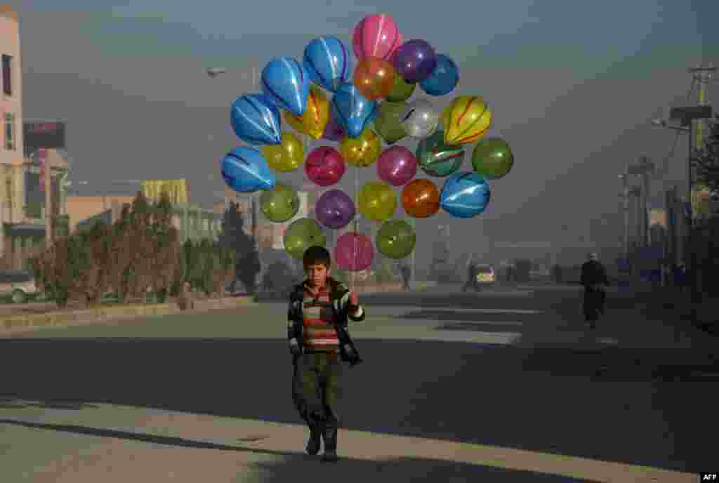 Afghan boy Hizbullah, 10, walks as he looks for customers to buy his balloons on the streets of Mazar-i-Sharif.