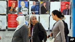 Des Tunisiennes devant un mur recouvert d'affiches de la campagne électorale, le 21 novembre 2014.