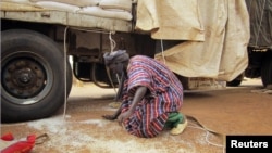 A man gathers rice spilled from a humanitarian food convoy that arrived from the Malian capital Bamako in the northeastern city of Gao, June 12, 2012. 
