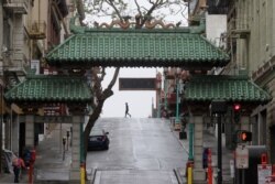A pedestrian crosses Grant Street behind the Dragon Gate, an entrance to Chinatown in San Francisco, Saturday, April 4, 2020.