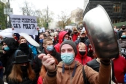 Restaurant workers protest a tighening of coronavirus restictions, including lockdowns on weekends, in Kyiv, Ukraine, Nov. 11, 2020. The sign reads "Weekend lockdowns put a million people out of work."