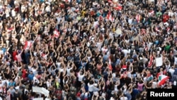 Demonstrators carry national flags and gesture during an anti-government protest in Beirut, Lebanon, Oct. 19, 2019.