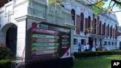 People walk past polling results displayed on a giant screen outside a vote counting center following the parliamentary election in Colombo, Sri Lanka, Nov. 15, 2024.