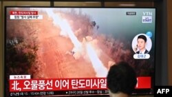 A woman watches a television screen showing a news broadcast with file footage of a North Korean missile test, at a train station in Seoul on June 26, 2024.