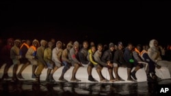 Refugees and migrants from many different African nationalities sit aboard an overcrowded rubber boat leaving Libyan territorial waters early Sunday, March 5, 2017. 
