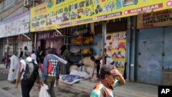 FILE - Kenyans walk past closed shops in the capital after an attack on a hotel complex, claimed by al-Shabab, in Nairobi, Kenya, Jan. 18, 2019.