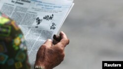 A man smokes a cigar as he reads a local newspaper in Havana, Cuba, Sept. 13, 2016.