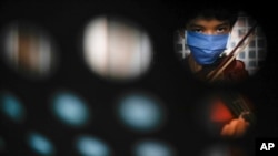 A youth wears a protective face mask amid the new coronavirus pandemic as he plays his violin during free music lessons from Narciso Ernesto Pichardo at the Culture Center in La Pastora neighborhood of Caracas, Venezuela, Aug. 19, 2020. 