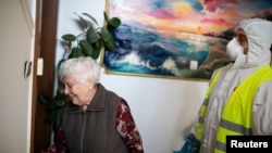 FILE - Municipal worker Ioannis Chrysanthakopoulos carries goods for pensioner Vassiliki Chalari, via the Athens municipality's "Help at Home Plus" program that supports vulnerable individuals, in Athens, Apr. 7, 2020.