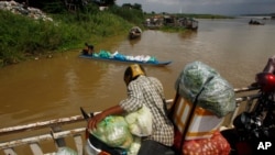 A vendor, foreground, stands on a ferry together with his goods before crossing the Mekong river in Dei Edth village at the outskirt of Phnom Penh, Cambodia, July 22, 2020. 