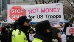 South Korean protesters hold banners during a rally as police officers stand guard near the Foreign Ministry in Seoul, South Korea, Feb. 10, 2019. South Korea and the United States are negotiating how much Seoul should pay for U.S. military presence.