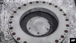 This photo provided by NASA on Oct. 11, 2023, shows the outside of the Osiris-Rex sample collector with material from asteroid Bennu at middle right. The bulk of the sample is located inside. (NASA via AP)