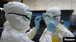 Health workers wearing protective clothing prepare themselves before to carrying an abandoned dead body presenting with Ebola symptoms at Duwala market in Monrovia, Aug.17, 2014. To try to control the Ebola epidemic spreading through West Africa, Liberia 