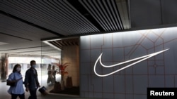 在中国北京的一个购物中心，人们走过体育用品零售商耐克公司的商店（2021年3月25日）。