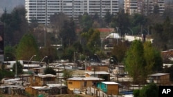 FILE - Makeshift homes fill the Vila Ermita de San Antonio neighborhood, below, near high-rise apartments located in the Las Condes sector of Santiago, Chile.