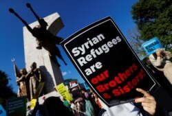 FILE - Demonstrators hold placards in support of Syrian refugees during a protest against Turkish government's recent refugee policies in Istanbul, Turkey, July 27, 2019.