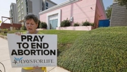 FILE - An abortion-rights opponent sings to herself outside the Jackson Women's Health Organization clinic in Jackson, Miss., Oct. 2, 2019.