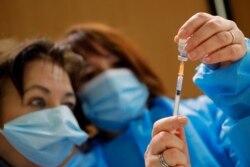 FILE - Nurses prepare a Pfizer-BioNTech COVID-19 vaccine to be administered to a health care worker at a coronavirus vaccine center in Poissy, France, January 8, 2021.