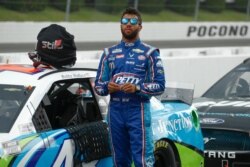 FILE - Bubba Wallace stands by his car before the start of the NASCAR Cup Series auto race at Pocono Raceway, in Long Pond, Pennsylvania, June 28, 2020.